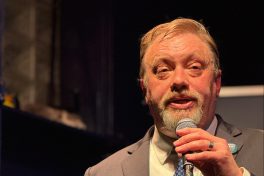 Aaron Klemz speaking with a microphone